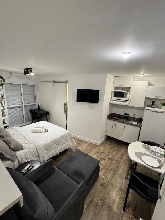 a room with a bed and a couch and a kitchen at Studio no Coração do Jardins Moderno e Sofisticado in São Paulo