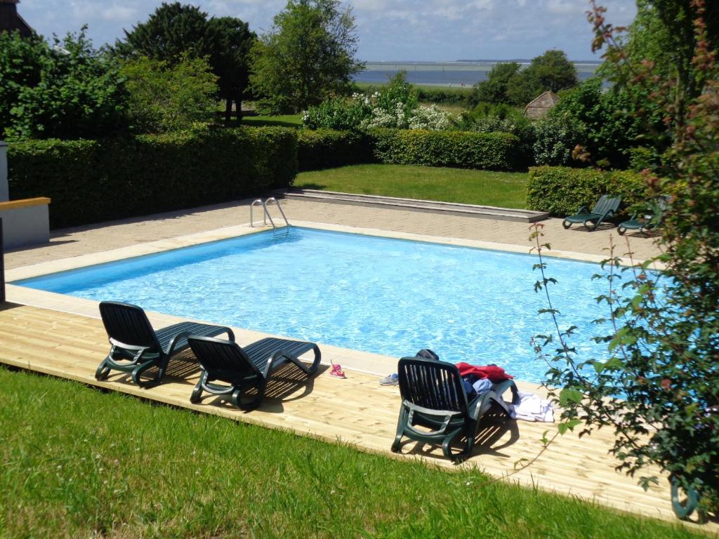a swimming pool with two chairs and a couple at Le Cap Hornu in Saint-Valery-sur-Somme