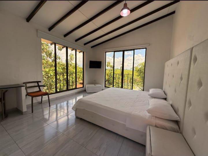a bedroom with a large bed and large windows at hotel boutique in Pereira