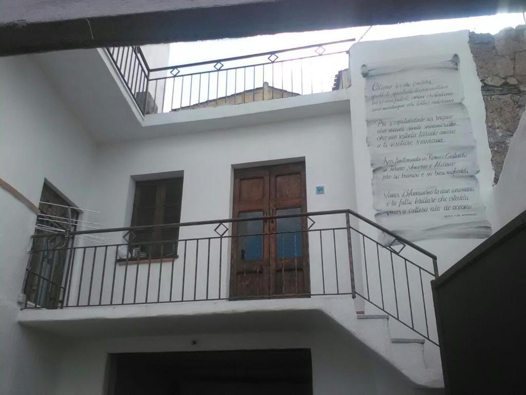 een wit gebouw met een trap en een houten deur bij B&b barbaricino iun F1442 in Oliena