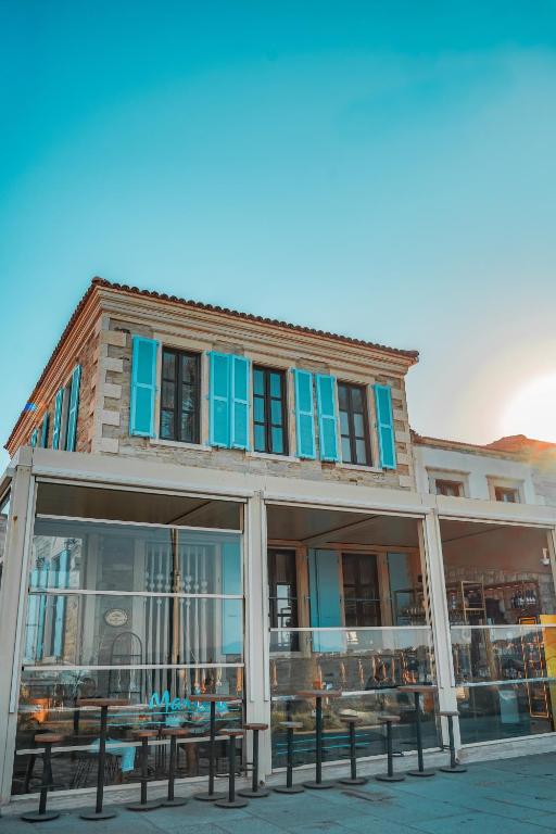 a building with blue windows and benches in front of it at Marina Foça Hotel in Foça