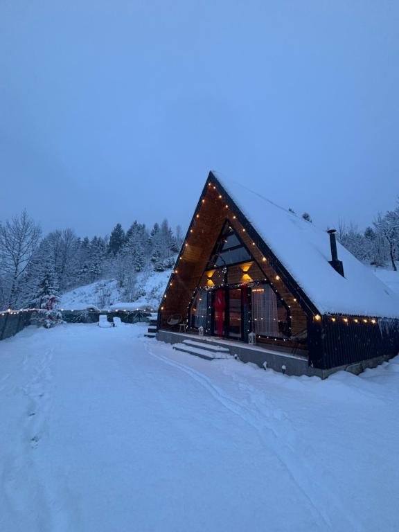 a log cabin in the snow with lights on it at Riverside A-frame in Borşa