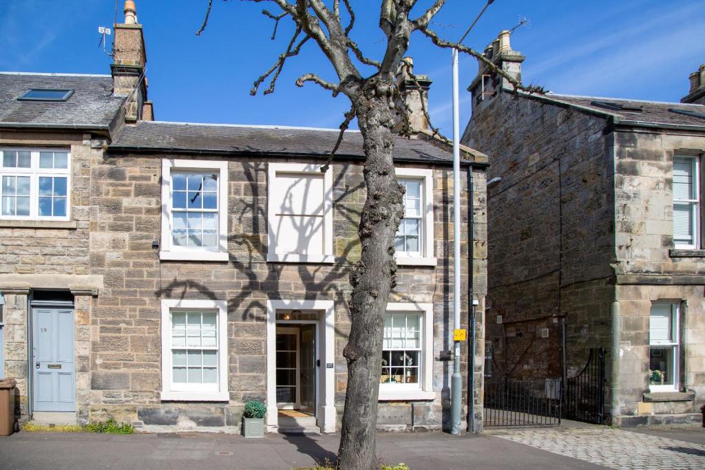 an old stone house with a tree in front of it at Wilson House in St. Andrews