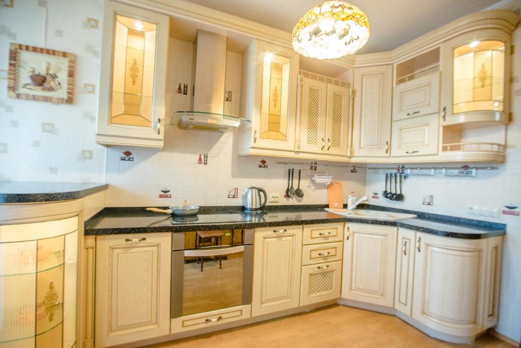 a kitchen with white cabinets and a chandelier at Sovetskaya 50 in Tomsk