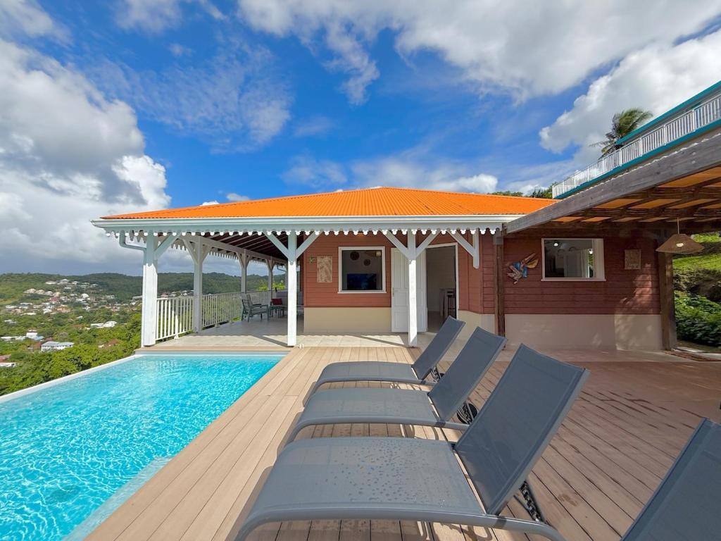 a swimming pool with lounge chairs next to a house at Villa Altaïa - Sea View & Infinity Pool in Les Trois-Îlets