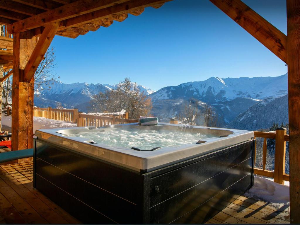 a hot tub on a deck with mountains in the background at Chalet Bendo - OVO Network in Villarembert
