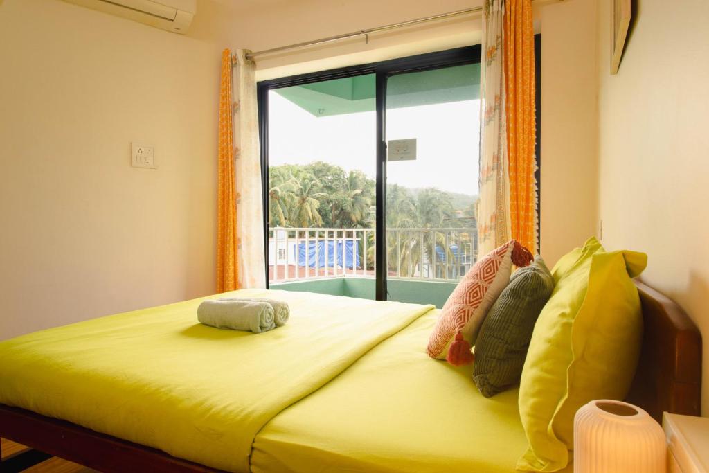 a bedroom with a bed with a large window at Odd Table-Social Homestay in Mandrem