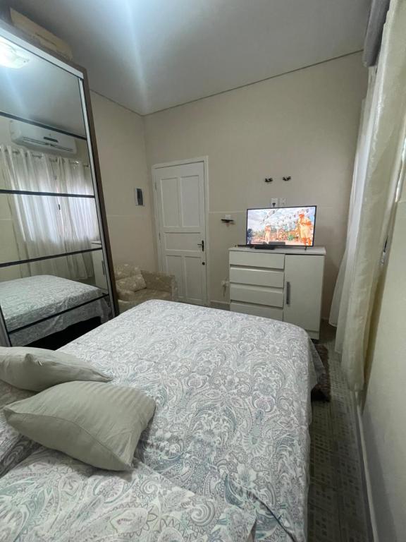 a bedroom with a bed and a television in it at Casa Centro de Caraguatatuba in Caraguatatuba