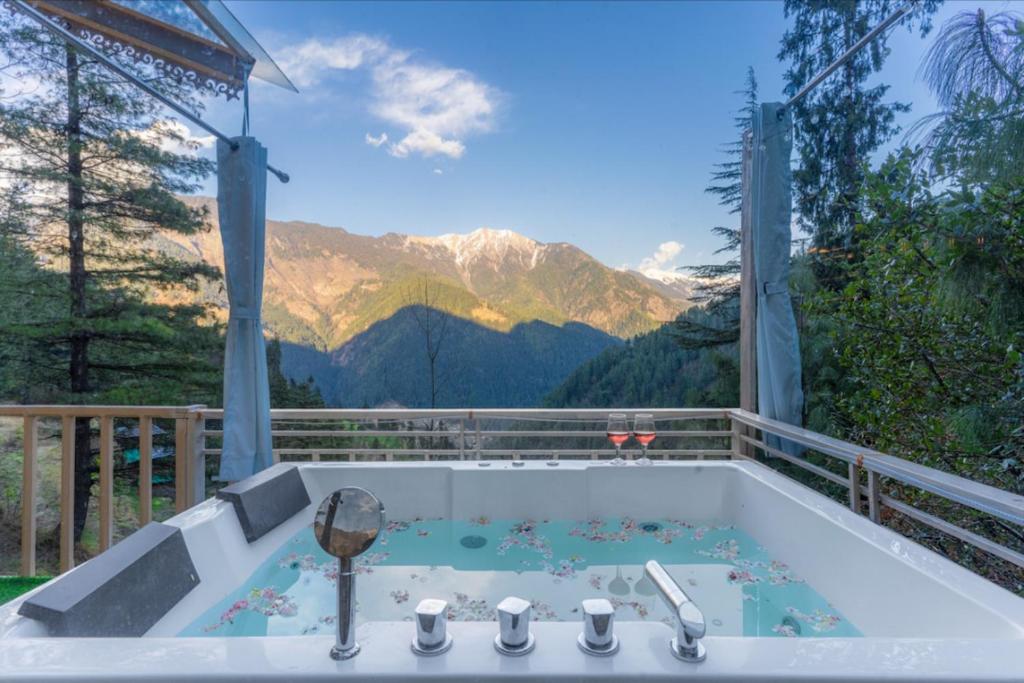 a bath tub with a view of a mountain at UrWish TreeHouse cottageJacuzzi in Jibhi