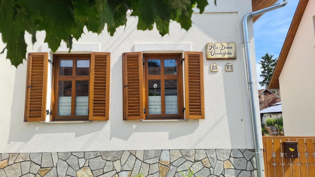 two windows on the side of a building with wooden shutters at Kis-Duna Vendégház in Dunabogdány