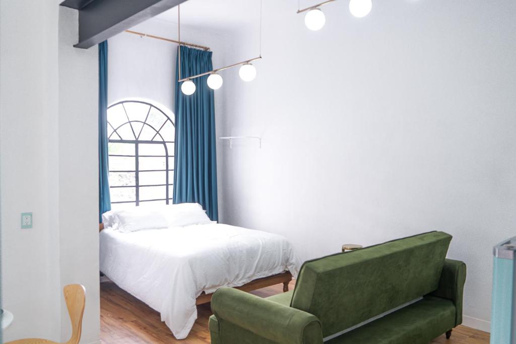 a bedroom with a bed and a green chair at La Casona in Guadalajara