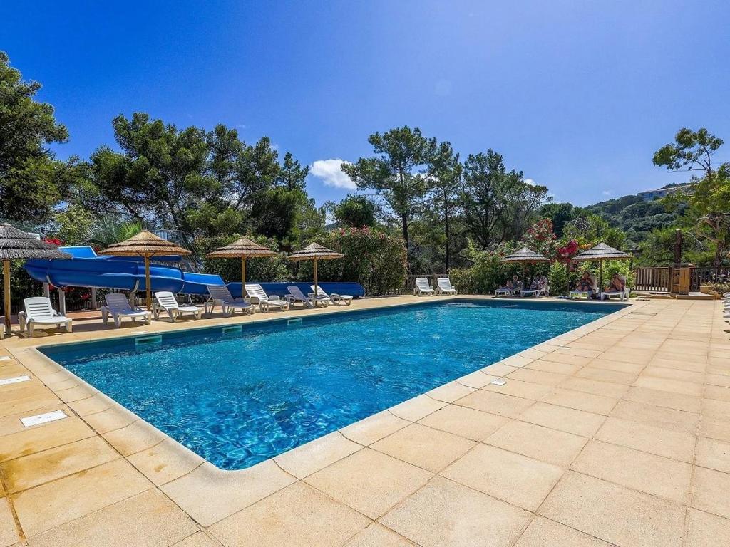 a swimming pool with chairs and umbrellas in a yard at ZEcamping 3 étoiles avec terrain multisports mini golf 2km plage dog friendly in Cargèse
