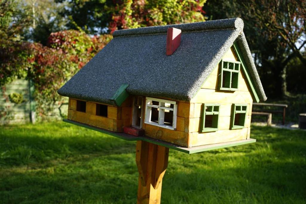 a toy house on a wooden post in the grass at Ferienhaus Alex in Großefehn 