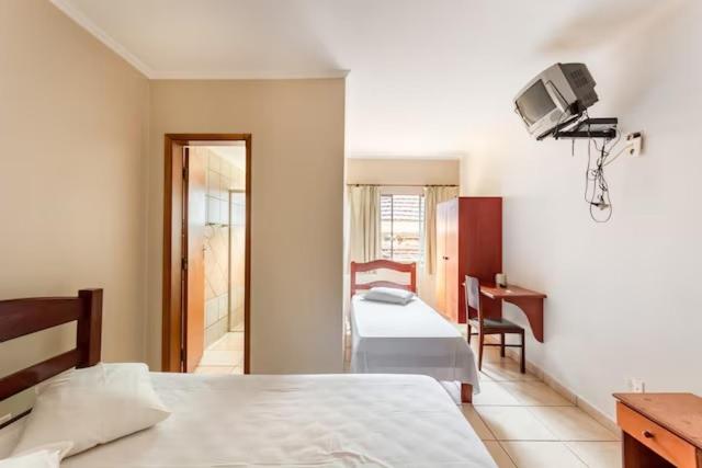 a bedroom with a bed and a desk and a television at Agrishow 26 - Apartamento Single e Duplo in Ribeirão Preto