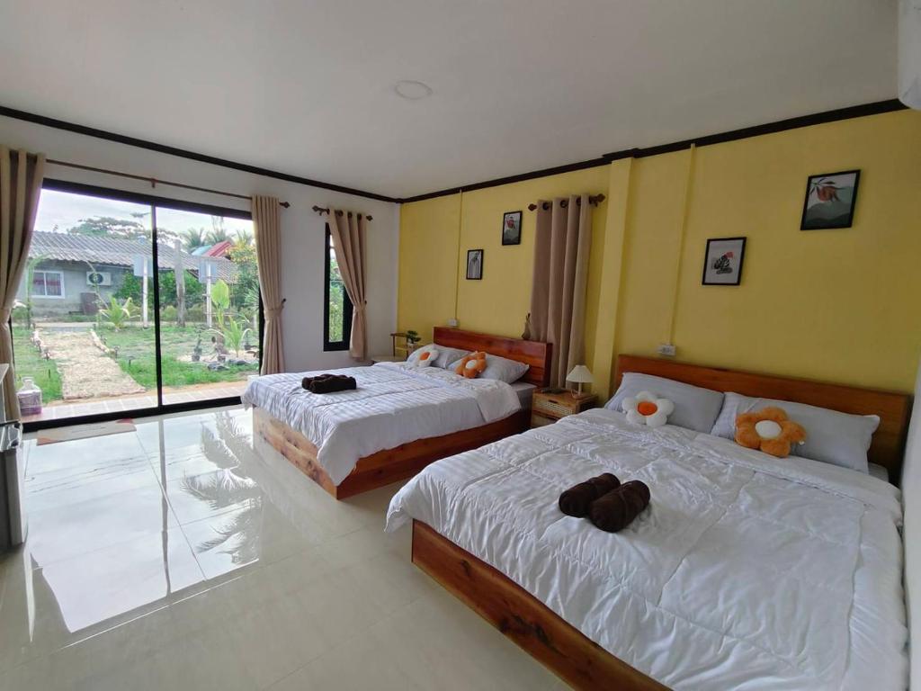 a bedroom with two beds and a large window at Langkao Homestay Kohlibong หลังเขาโฮมสเตย์ เกาะลิบง in Ko Kwang