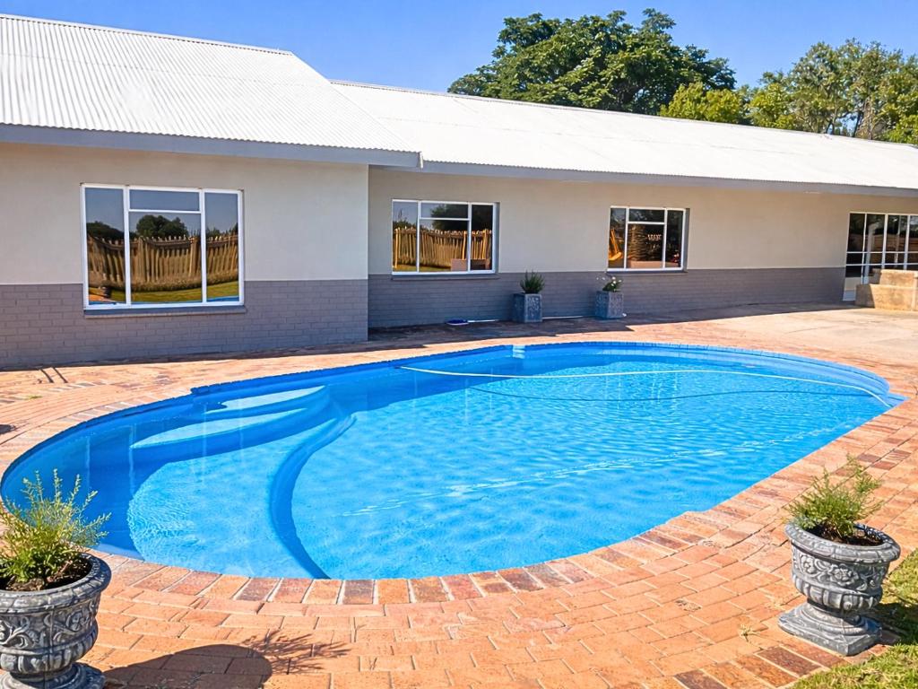 a large blue swimming pool in front of a house at The Bloemhof Stay in Bloemhof