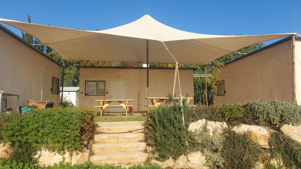 a patio with a table and an umbrella at אירוח משק 42 in Sheʼar Yashuv