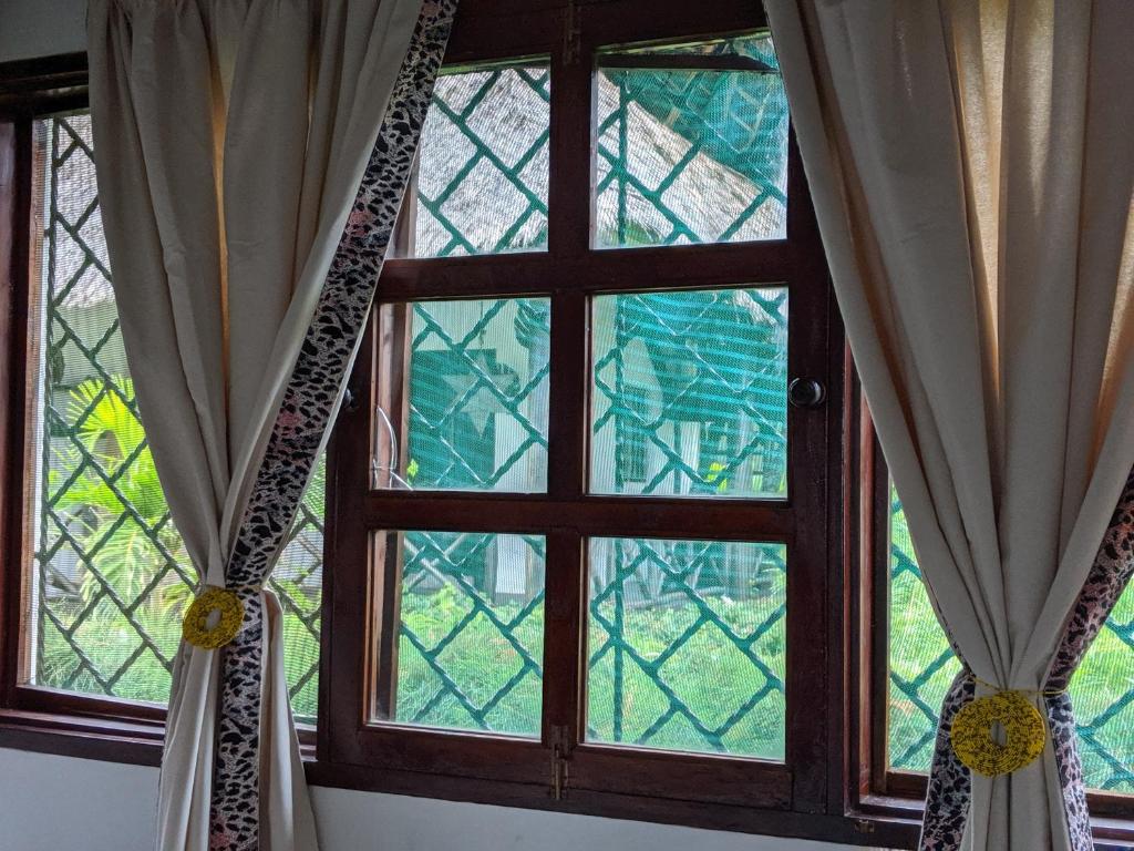 two windows in a room with curtains in front at Nelion Villas in Mambrui