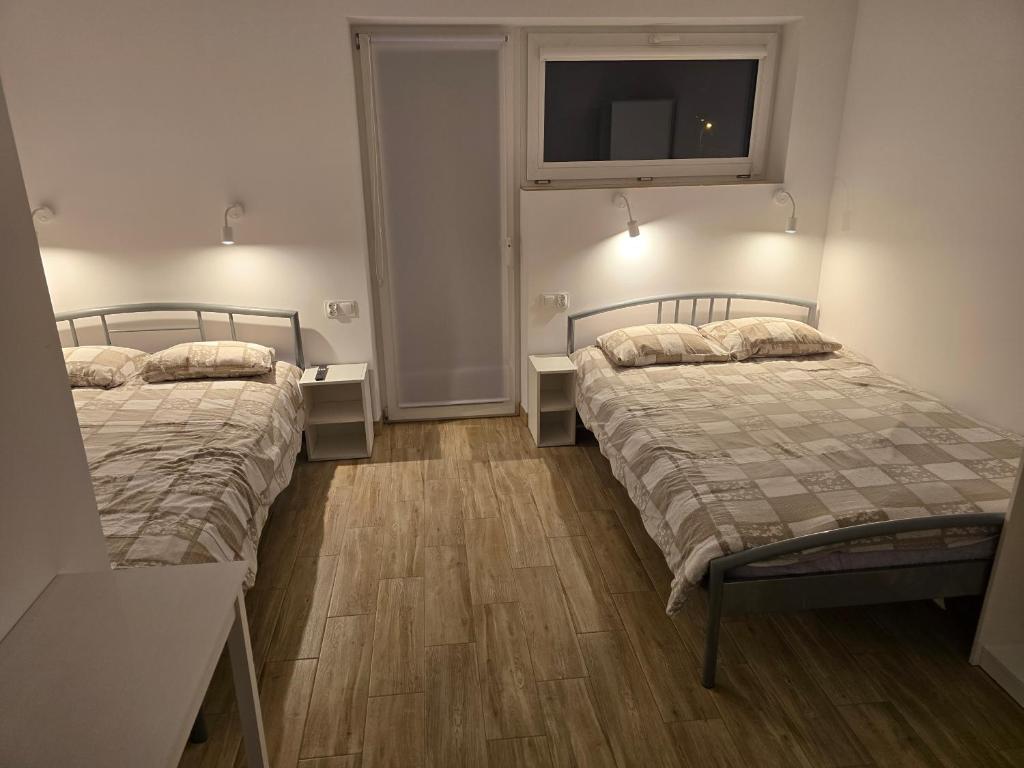 a bedroom with two beds and a tv on the wall at Rent0nline Brwinow Rooms in Brwinów