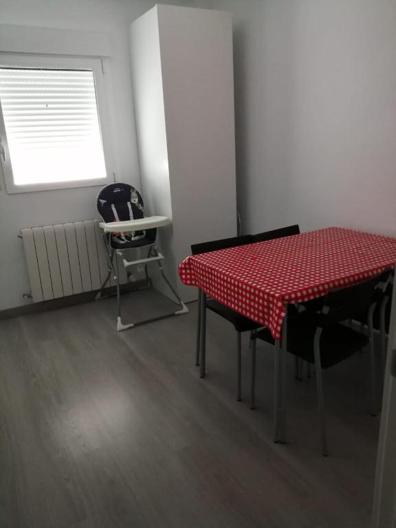 a red table and chairs in a room with a window at Como en tu casa in Zaragoza