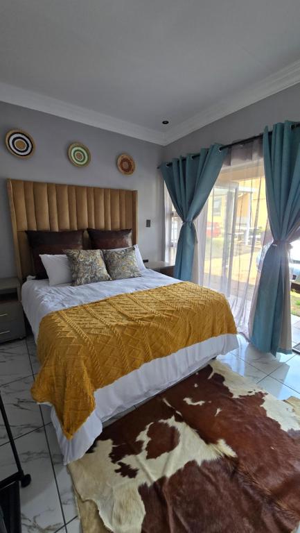 a bedroom with a large bed with blue curtains at HUZULA Royal Residence in Empangeni