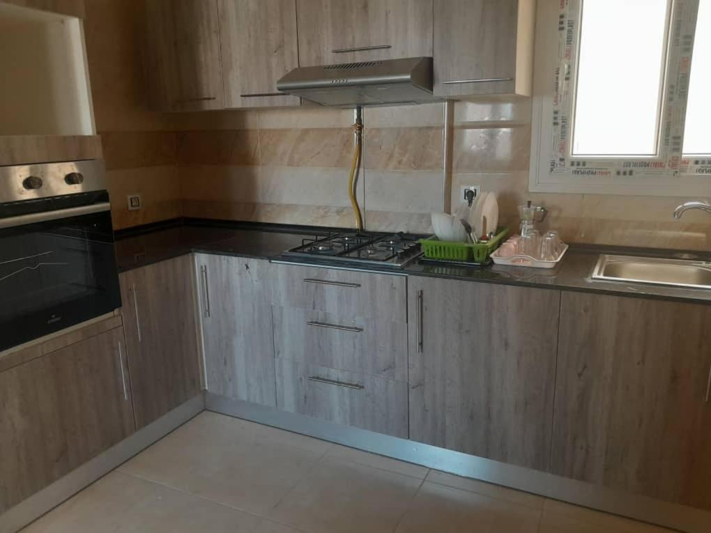 a kitchen with wooden cabinets and a stove top oven at Appartements Mimosa in Tefeschoun