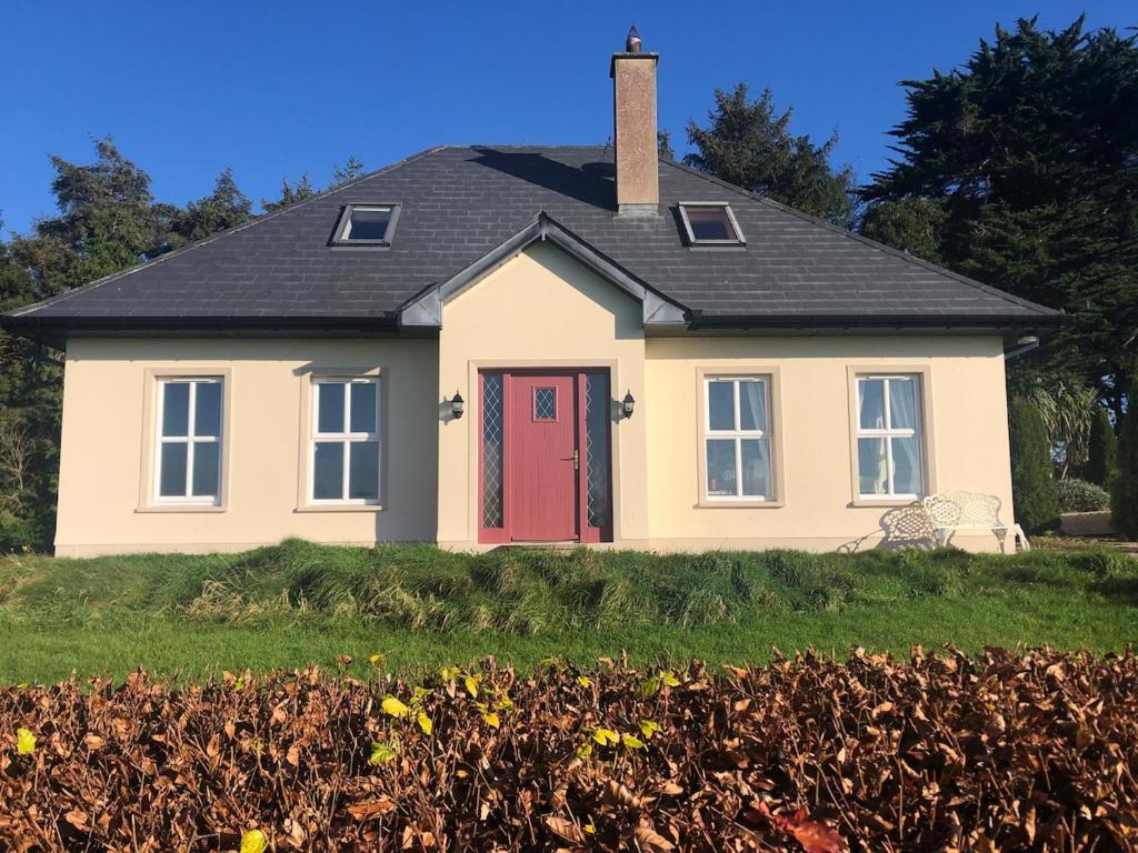a house with a red door in a field at Ashmount Lodge in Ballynageragh