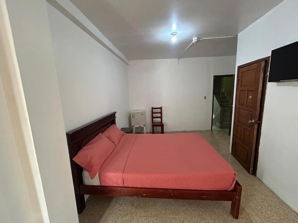a bedroom with a bed with a red bedspread at Hotel luque in Guayaquil