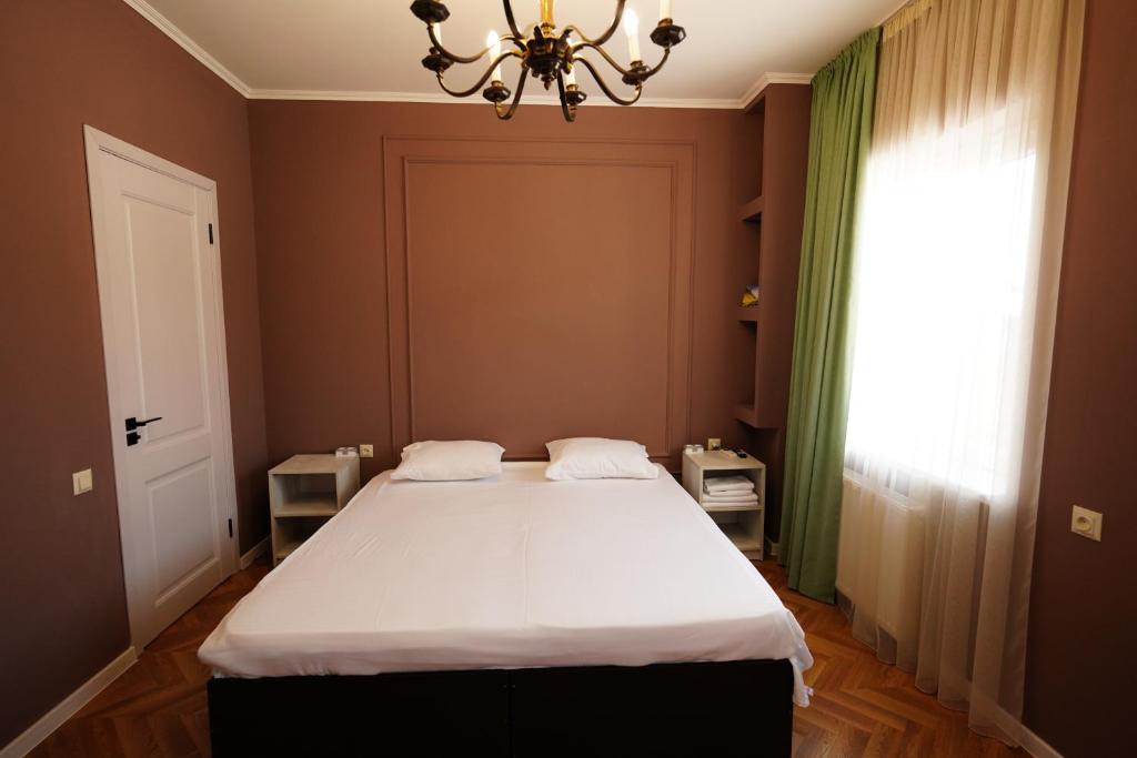 a bedroom with a large bed with a chandelier at Hotel Maisis Ezo in Kutaisi