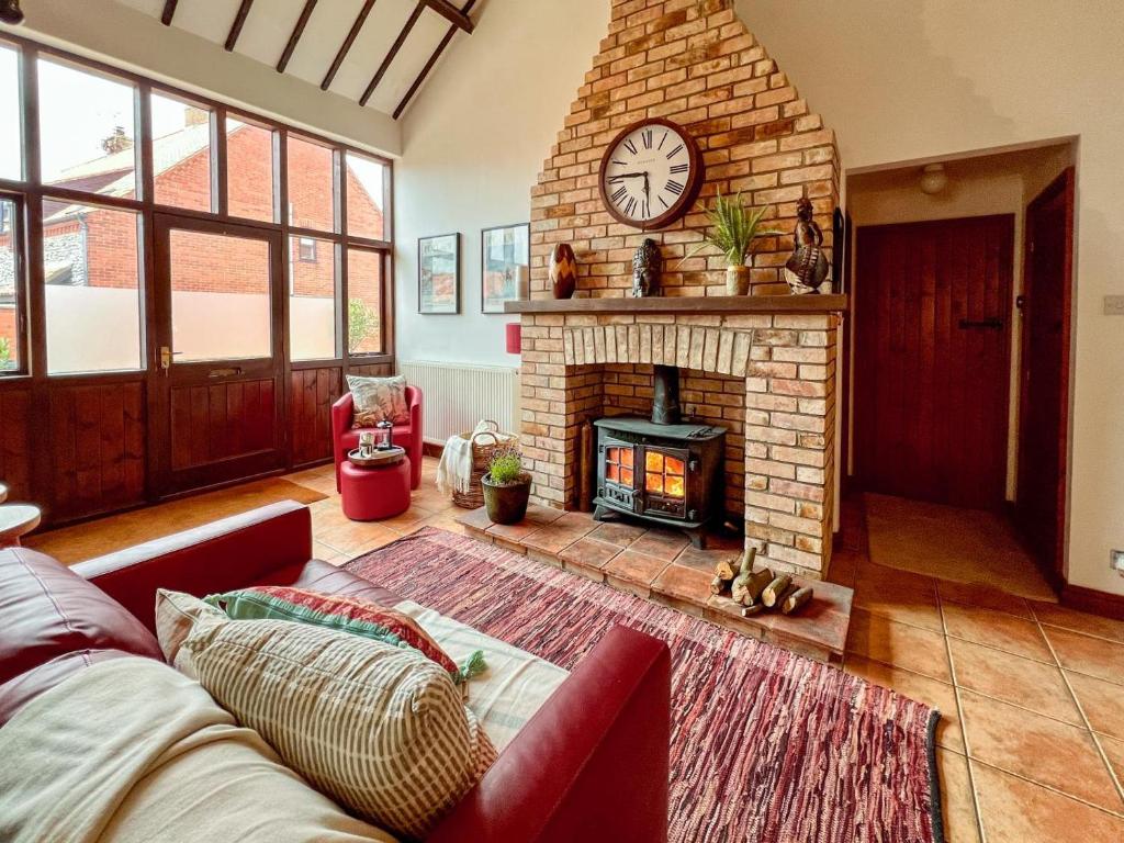a living room with a brick fireplace with a clock at 3 Bed in Holt oc-1331 in Bodham