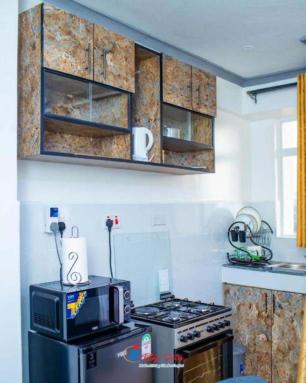 a kitchen with a stove and a microwave at Tataji Suites in Kisii