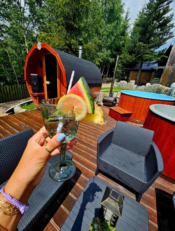 a woman holding a drink on a table next to a picnic table at Alpakowy raj in Nowy Targ