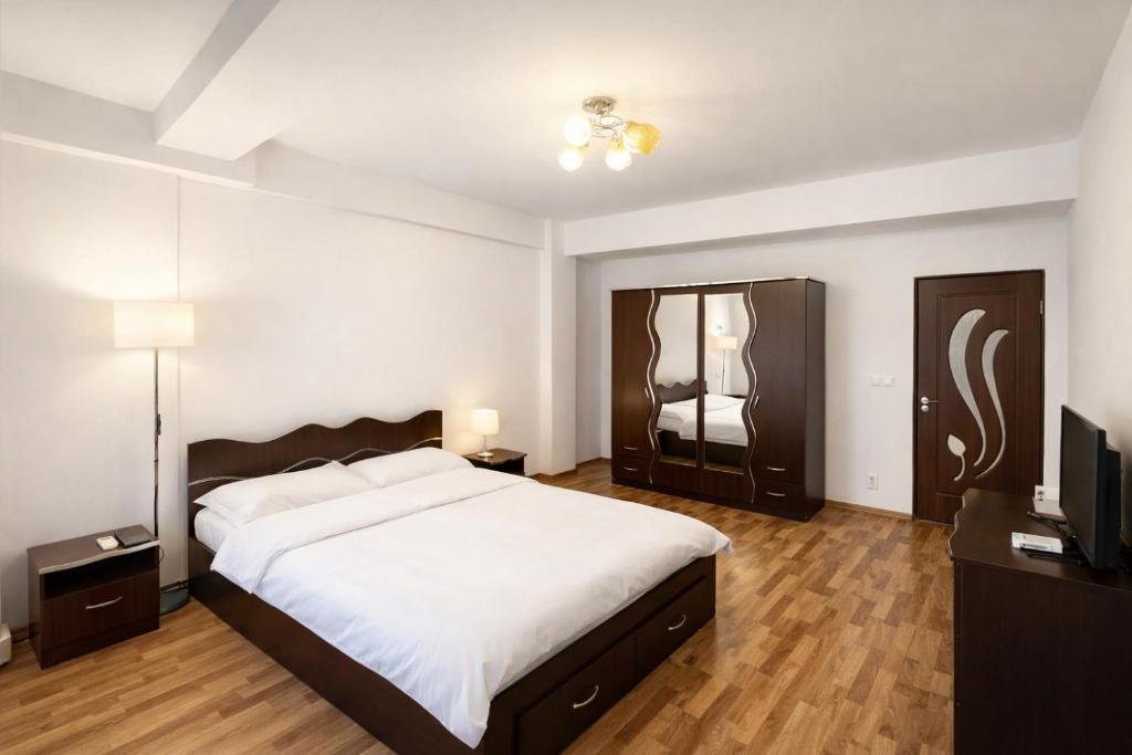 a bedroom with a large bed and a flat screen tv at Warm Place In Old Town in Bucharest