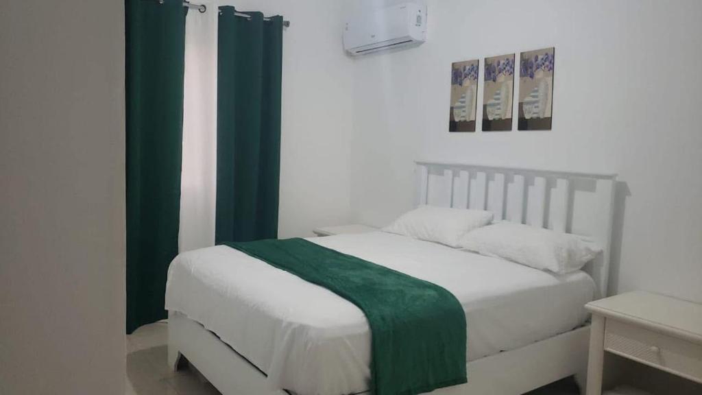 a bedroom with a bed with a green blanket on it at Hotel Dieux Internacional in Pedernales