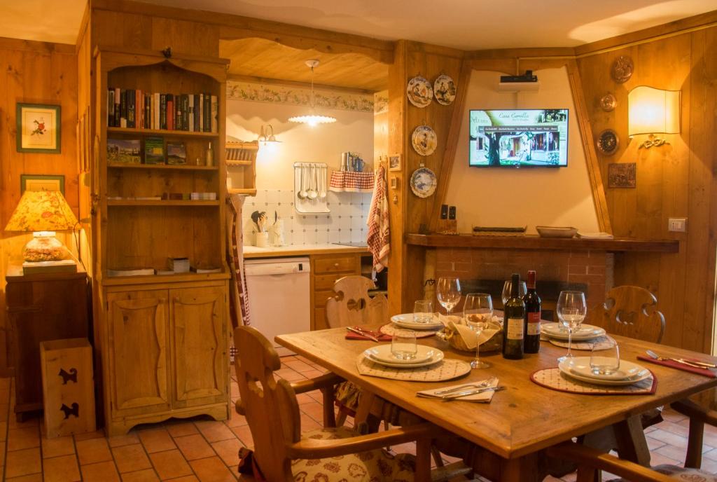 uma cozinha com uma mesa de madeira e copos de vinho em Casa Camilla Holiday em Folgaria