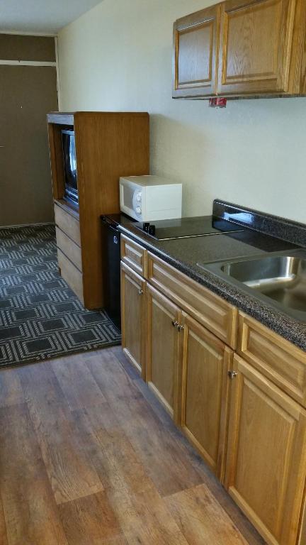 cocina con armarios de madera y encimera en Americourt Extended Stays, en Kingsport