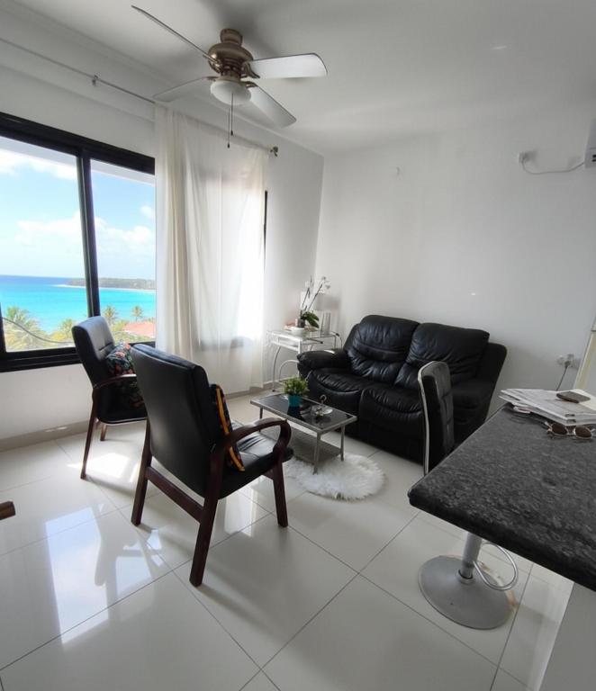 a living room with a black leather couch and chairs at על הים in Nahariyya