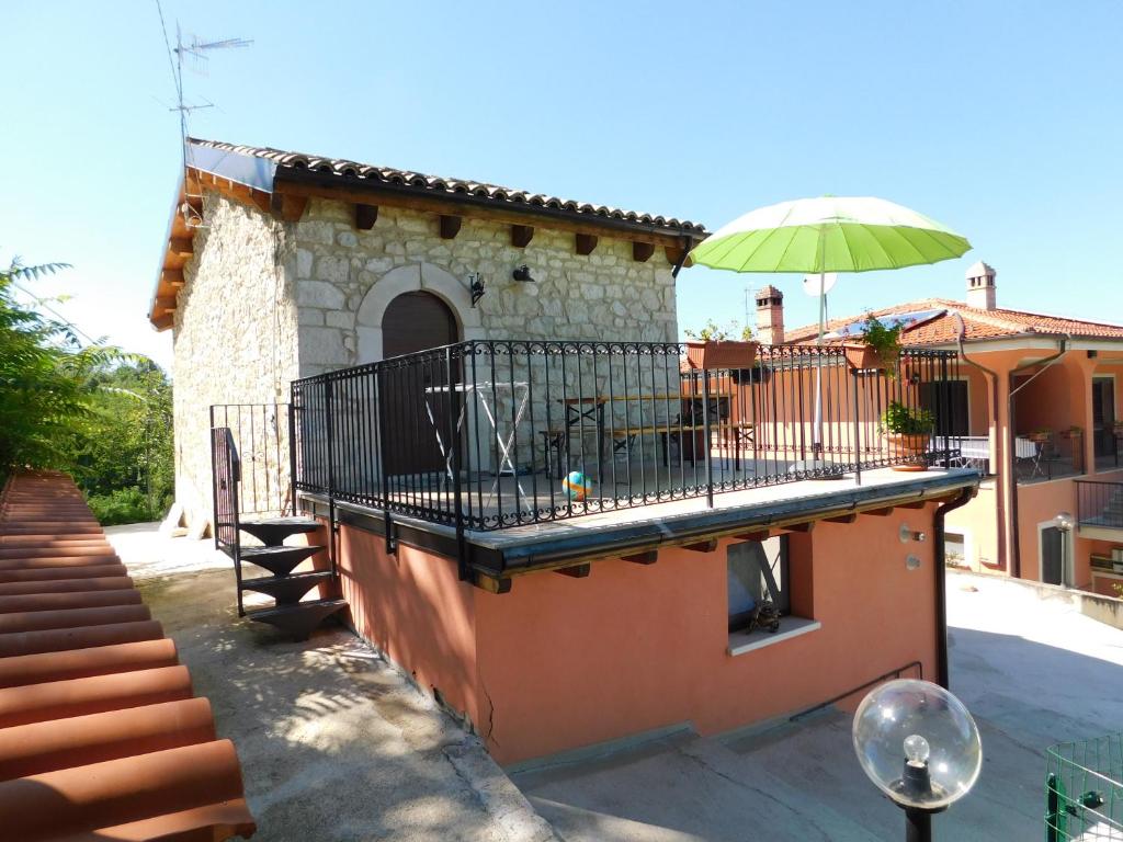 Casa con balcón con sombrilla verde en B&B Masseria Majella en Abbateggio