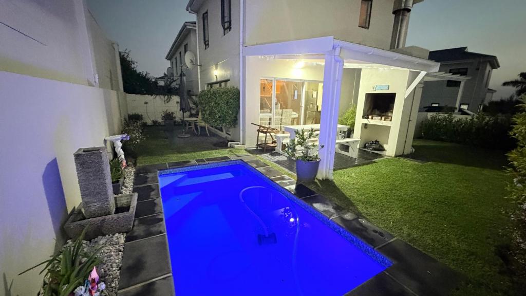 a blue swimming pool in the yard of a house at Villa on Private Estate with Pool in Hermanus