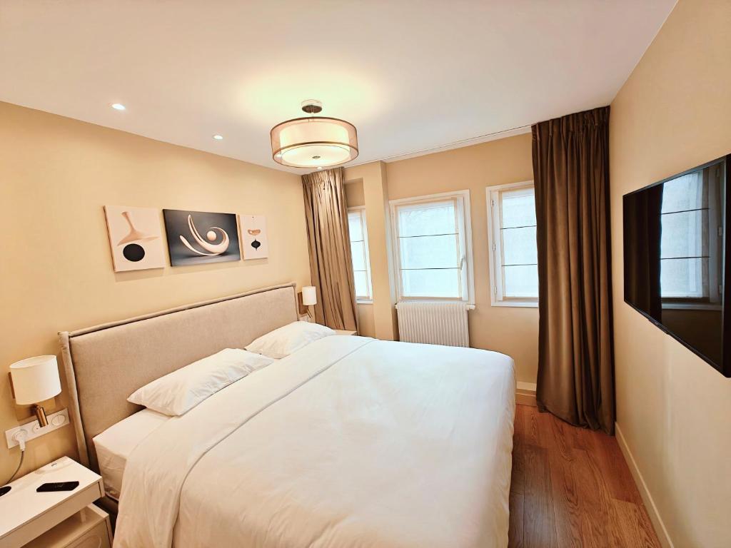 a bedroom with a white bed and a television at SCI Gomis Invest in Issy-les-Moulineaux
