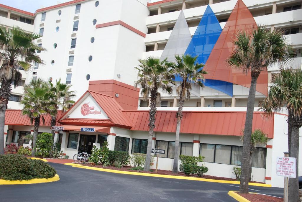 a hotel with palm trees in front of a building at Harbour Beach Resort in Daytona Beach