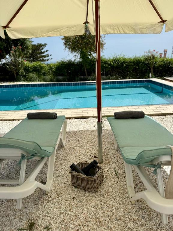 two chairs and an umbrella next to a swimming pool at ART BLUE Residence - Pool Access Apartment in Aghia Marina