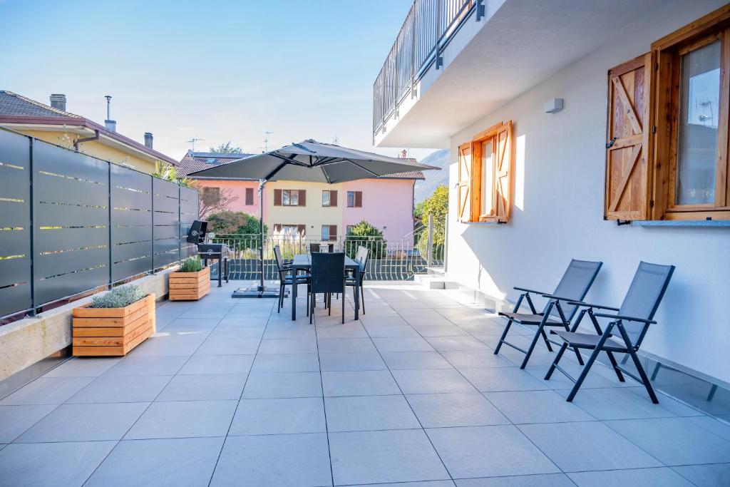 a patio with chairs and tables and an umbrella at Casa Simona in Dervio