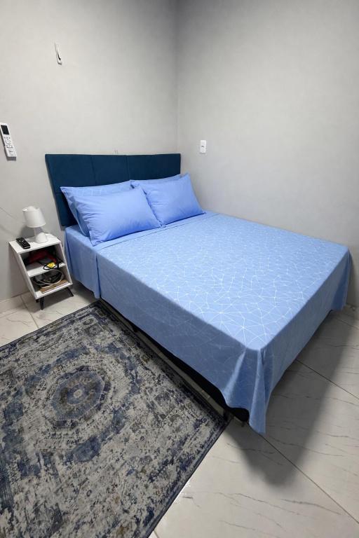 a bedroom with a bed with blue sheets and a rug at AmazHost - Casa azul próxima da Basílica de Nazaré in Belém
