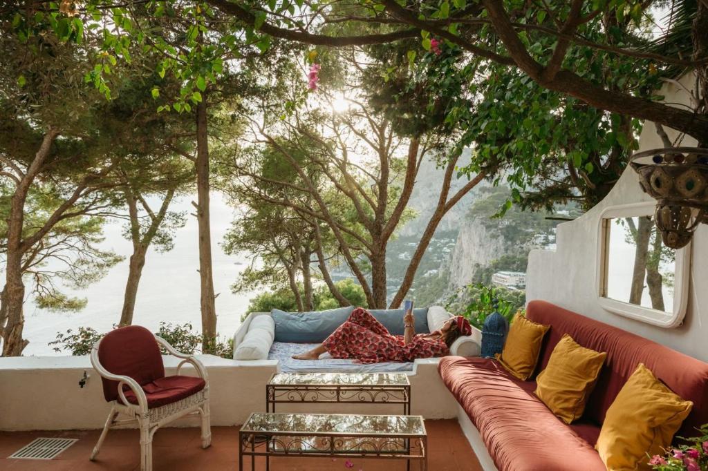 a living room with a couch and chairs and trees at Villa Guya in Capri