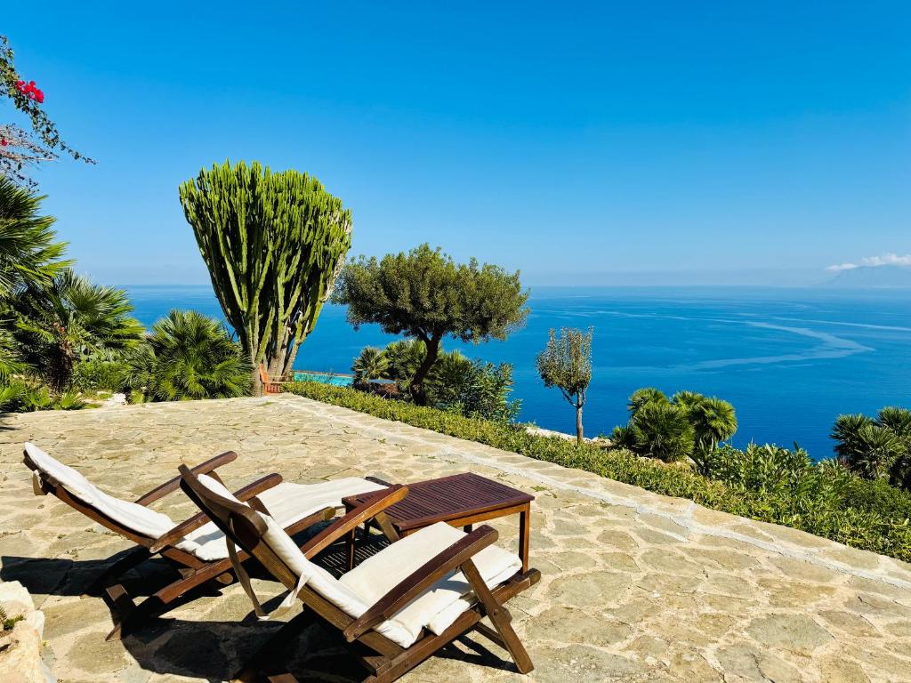 two chairs and a table on a patio with the ocean at Baglio La Luna - B&B in San Vito lo Capo