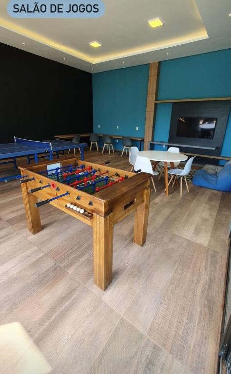 a ping pong table in a room with tables and chairs at Apto com área de lazer estilo resort in Parnamirim