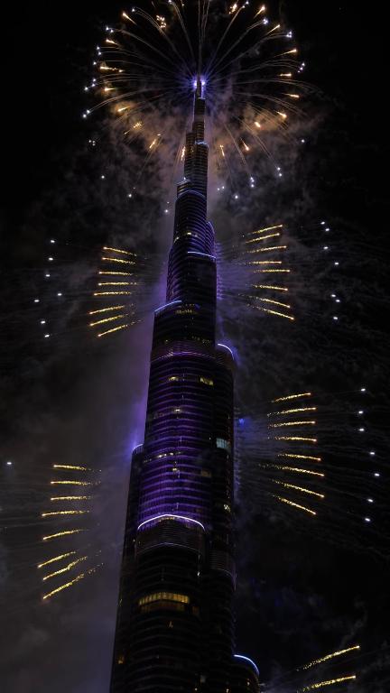 a tall building with fireworks in the sky at Private Room in Luxurious 3BR Apartment with BURJ KHALIFA view in Downtown near Dubai Mall in Dubai