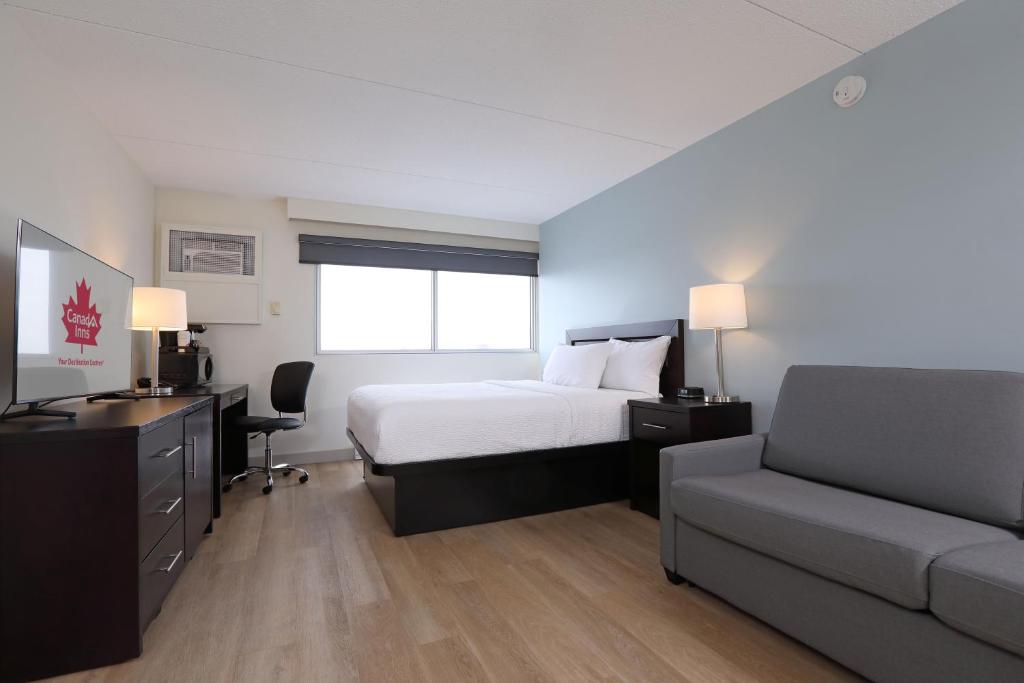 a bedroom with a bed and a desk and a couch at Canad Inns Destination Centre Polo Park in Winnipeg
