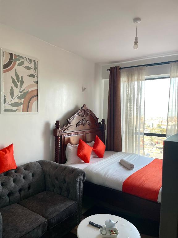 a bedroom with a bed and a couch and a window at T-Homes in Nairobi